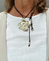 Collar con dije grande de bronce con forma orgánica y textura rugosa, suspendido de un cordón negro. Incluye cordones intercambiables.