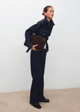 Pantalón de jean estilo flare con tiro medio, cierre de cordones en la cintura, cinco bolsillos y costuras a contratono.