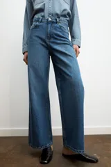 Jeans de tiro alto con diseño de pierna ancha y cinco bolsillos. Cuenta con cierre frontal mediante cremallera y botón metálico.