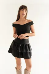 Pollera mini de seda fría con acabado tornasolado, diseño de tiro alto con faja en la cintura y falda con volados escalonados que aportan volumen.