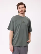 Remera negra de corte holgado con pequeño logo bordado en el pecho que incluye un diseño de pez y la marca Rusty.