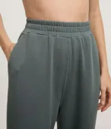 Pantalón deportivo femenino color verde oscuro, confeccionado en modal, con corte recto y largo. Presenta cintura elástica y detalle de trenzadora en la parte delantera.