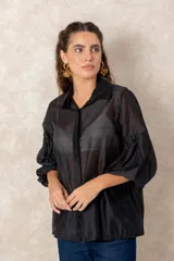 Camisa de organza negra con transparencias, cuello clásico y mangas globo con puños elásticos.