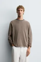 Jersey de manga larga, cuello redondo y calce relajado, color negro con efecto lavado y textura tejida.