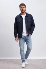 Chaqueta tipo sobrecamisa o 'shacket' de color azul marino, con cuello camisero, cierre frontal de botones y dos bolsillos de parche con solapa y botón en el pecho.