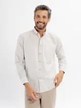 Camisa de manga larga con diseño de rayas finas, cuello con botones y bolsillo frontal. Presenta cierre de botonadura frontal y corte regular.