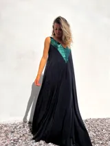 Vestido largo de corte holgado en color negro, con escote en V profundo decorado con apliques de lentejuelas en color verde esmeralda.