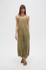 Mono de algodón color verde oliva, con textura plisada, escote en V y tirantes finos tipo lencero. Presenta bolsillos frontales y corte holgado.