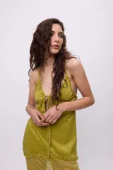 Vestido midi de tela semitransparente con acabado brillante en color verde esmeralda. Presenta un diseño con volados en los recortes, escote con cordón ajustable y breteles finos.