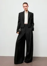 Pantalón wide leg de tiro alto color negro, con diseño largo, bolsillos laterales, detalle de pinzas y cierre oculto con botón, gancho y cremallera.