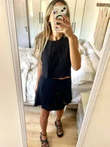 Conjunto de dos piezas compuesto por un top sin mangas de corte recto y una pollera corta acampanada, ambos en color negro.