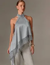 Blusa de satén color gris con cuello halter alto y fruncido, diseño sin mangas, corte asimétrico y detalle de encaje en el borde inferior.