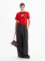 Remera de jersey pesado color blanco, con cuello redondo en contraste negro y estampa central de un corazón con diseño animal print atravesado por una flecha.