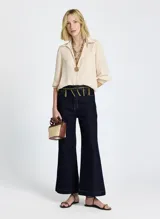 Pantalón de jean de tiro alto, color azul oscuro, con corte flare y costuras en color ocre.