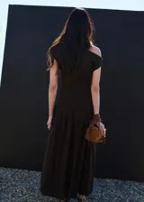 Vestido largo marrón de diseño asimétrico y corte evasé, con cuello barco y manga corta.