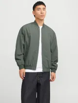 Campera bomber verde militar, liviana, de manga larga con cuello baseball y corte cómodo. Tiene cierre frontal de cremallera, bolsillos delanteros y puños de canalé.
