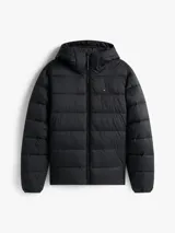 Campera acolchada de color negro confeccionada en tejido ripstop de nailon con acabado repelente al agua. Presenta un diseño con relleno térmico, capucha fija ajustable con cordón, cierre frontal de cremallera y bolsillos laterales con cierre. Incluye el logo de Tommy Hilfiger bordado en el pecho.