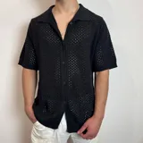 Camisa de manga corta confeccionada en tejido de punto calado, con cuello tipo polo y cierre frontal de botones.