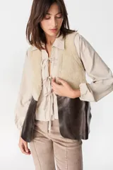 Chaleco de cuero marrón con interior y solapas de piel sintética color crudo. Diseño sin cierre, con corte recto y acabado texturizado.