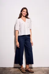 Blusa de viscosa color marrón, con escote en V, mangas cortas abullonadas y cierre frontal con botones. Cuenta con pequeños detalles bordados distribuidos por la prenda.