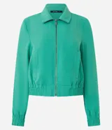 Campera bomber femenina color beige claro, confeccionada en tejido Airflow texturado. Presenta cuello solapa, cierre frontal de cremallera y puños y bajo elásticos.