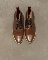 Botas acordonadas marrones de cuero vacuno con suela clara.