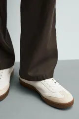 Zapatillas deportivas de hombre, de estilo retro, color blanco con puntera de gamuza color crema, detalle trasero en cuero negro y suela marrón.