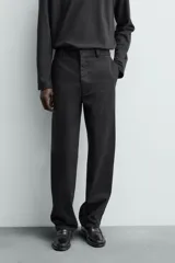 Pantalón chino de corte oversized confeccionado en tejido de algodón con estructura twill. Presenta bolsillos frontales, bolsillos traseros de vivo y cierre frontal con cremallera y gancho metálico oculto.