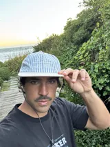 Gorro tipo gorra de visera plana, con paneles a rayas verticales azules y blancas, y visera blanca lisa. Presenta bordado en la parte frontal con el texto "LEVEIN", "MOOD THAT ONLY KNOW" y "SEE GOOD FIALN THINGS".