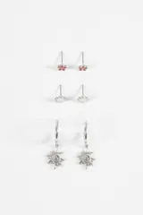 Set de tres pares de aros de metal plateado. Incluye un par de aros tipo stud con forma de flor con centro esmaltado en rojo, un par de aros tipo stud con forma de sol pequeño y un par de aros tipo argolla con dije colgante en forma de sol con diseño espiral.