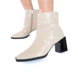 Botines de caña media confeccionados en cuero vacuno color trigo con textura tipo reptil. Presentan puntera cuadrada, cierre lateral discreto y tacón bloque de color negro brillante.