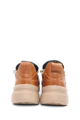 Championes deportivos acordonados de cuero, con diseño combinado en tonos beige, marrón y negro. Presenta suela de plataforma en color tostado y detalles metálicos en los ojales de los cordones.
