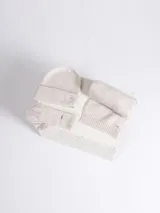 Set de accesorios de invierno en color beige melange, compuesto por un gorro tipo beanie de punto acanalado, un par de guantes de punto y una bufanda de punto con terminación acanalada.