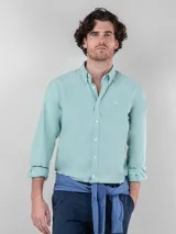 Camisa celeste de corte clásico, con cuello abotonado, manga larga y logo bordado en el pecho.