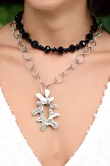 Collar doble compuesto por una gargantilla de cuentas facetadas negras y una cadena de eslabones plateados con un dije central de metal con forma orgánica irregular.