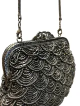 Bolso de mano estilo vintage, completamente bordado con mostacillas en tono peltre formando un patrón de escamas. Presenta una boquilla metálica dorada con cierre a presión y una cadena metálica a tono para llevar al hombro.
