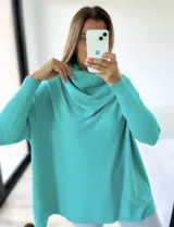 Polerón de punto color verde agua, con diseño mega oversize y cuello caído tipo polera. Presenta mangas largas con puños acanalados.