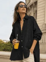 Camisa oversize de lino, color beige, con cuello camisero clásico, cierre frontal con botones, mangas largas con puños abotonados y bolsillo frontal aplicado.