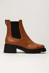 Bota tipo Chelsea de cuero color suela, con paneles elásticos laterales en color negro y suela track dentada de goma negra con taco cuadrado.