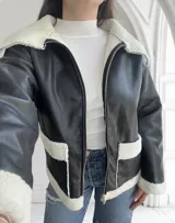 Campera de ecocuero negra con interior de corderito blanco, cierre frontal con cremallera y bolsillos laterales.