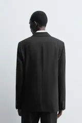 Blazer de corte regular confeccionada en tejido de lana italiana. Presenta cuello con solapas de pico, cierre frontal de botonadura cruzada, manga larga con puños abotonados, bolsillos de vivo en el pecho y bolsillos de solapa en la cadera.