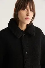 Campera negra de sherpa con cuello camisero, cierre con botones a presión y calce estándar.
