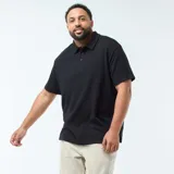 Polo negro de manga corta con cuello y tapeta de tres botones. El tejido presenta una textura de punto waffle o piqué sutil.