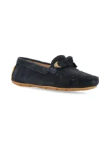 Mocasín de gamuza en color azul marino, con detalle de lazo frontal y herraje metálico dorado. Cuenta con suela de goma color caramelo.