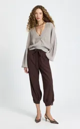 Pantalon de corte holgado color marrón, con cintura elástica ajustable mediante cordón, bolsillos laterales y puños abotonados en el bajo.