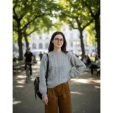 Sweater de punto color blanco marfil, con diseño de trenzas frontales, cuello redondo y mangas largas con puños elásticos acanalados.