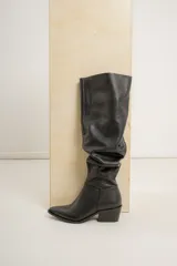 Bota alta de cuero color bordó, estilo bucanera, con caña fruncida y punta fina. Posee un taco bajo y ancho de color negro.