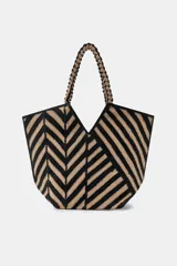 Bolso tipo shopper de yute 100%, con diseño de rayas y chevron en tonos negro y tostado, asas de hombro trenzadas y forma trapezoidal.