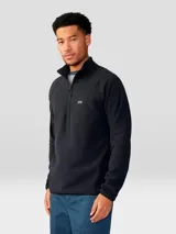 Buzo de polar con cierre frontal de 1/4, cuello alto y mangas raglán. Presenta un diseño minimalista en color negro con el logo de la marca bordado en el pecho.