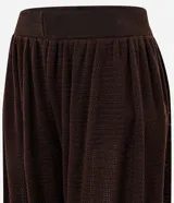 Pantalón de punto estilo aladino, color marrón oscuro, con diseño de tejido calado, cintura elástica y puños ajustados en los tobillos.